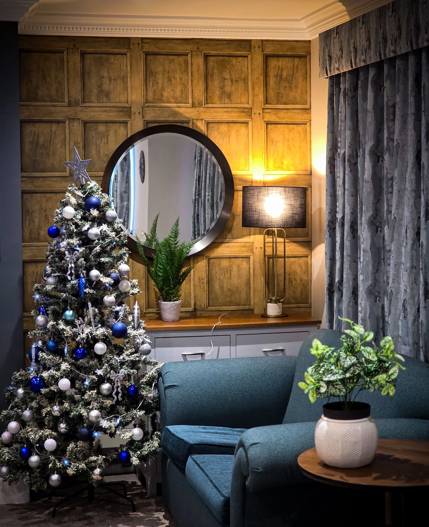 A beautifully decorated Christmas tree in a stylish living room with wooden panel walls. Perfect holiday ambiance.