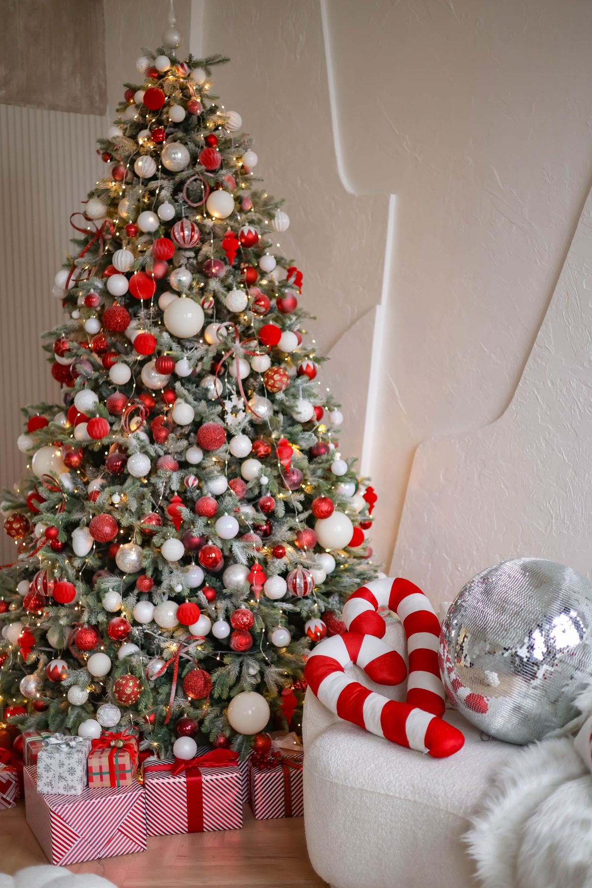 A beautifully decorated Christmas tree with gifts, candy canes, and ornaments create a festive holiday setting.