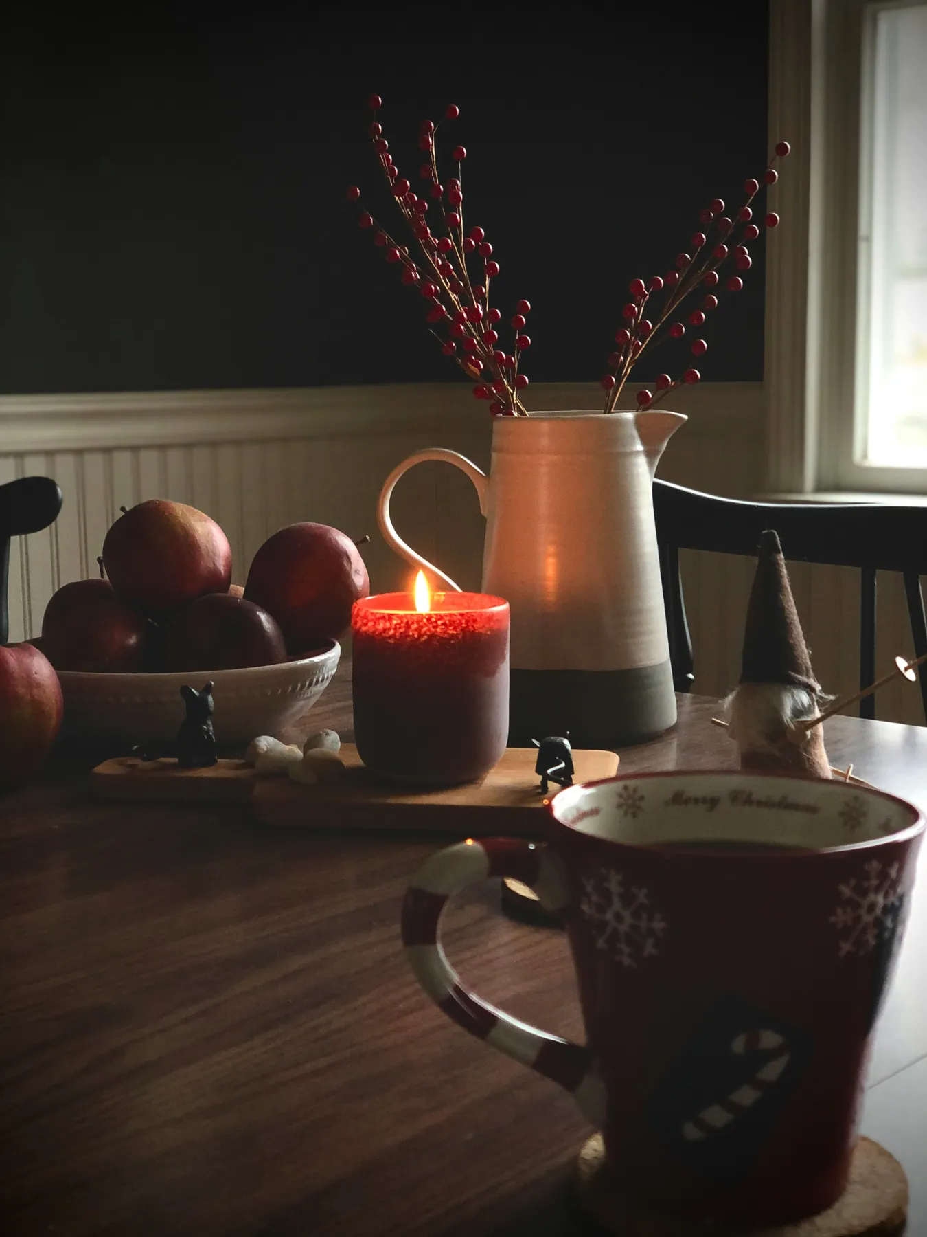 A candle burns on a wooden table on a chilly December day, a beautiful and cozy Christmas inspired scene.