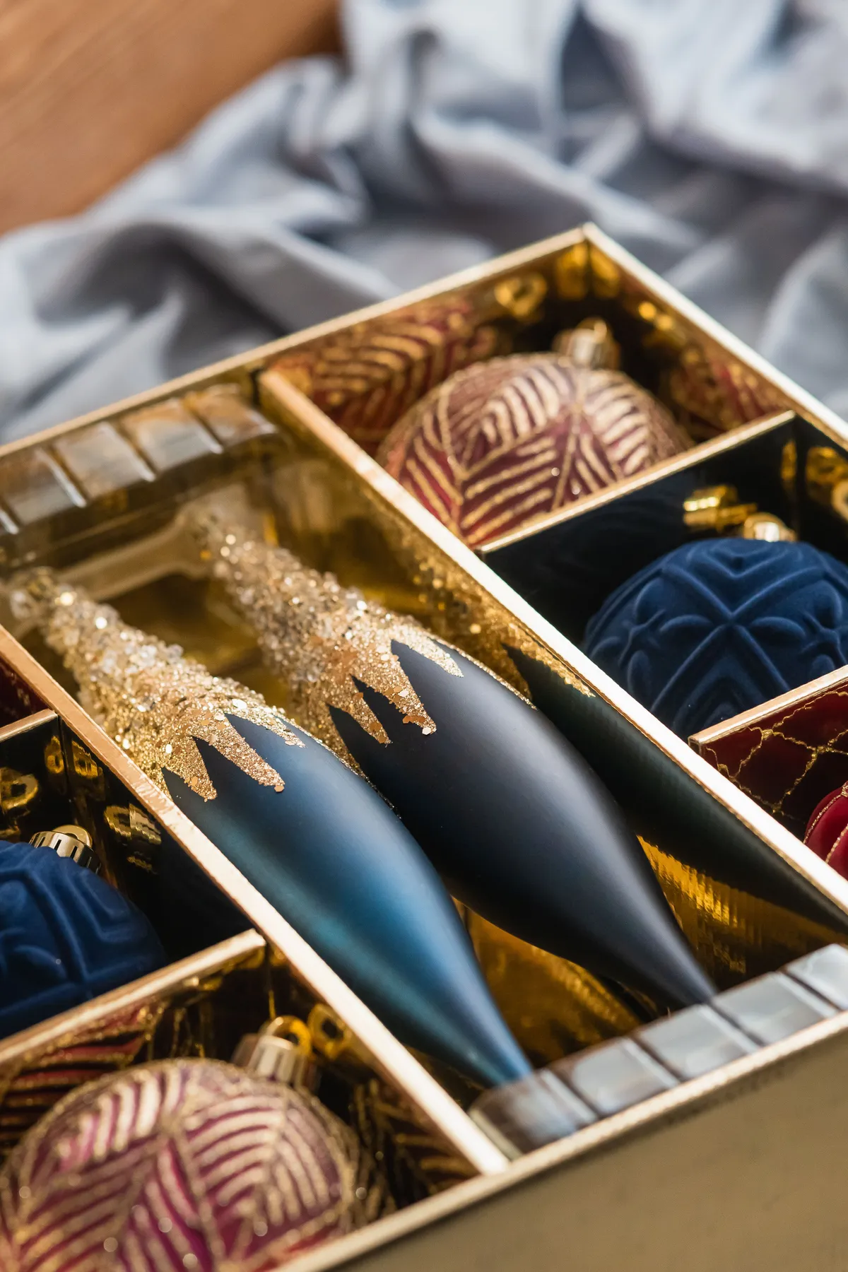 A close-up of a luxurious box of Christmas ornaments with rich textures and colors.
