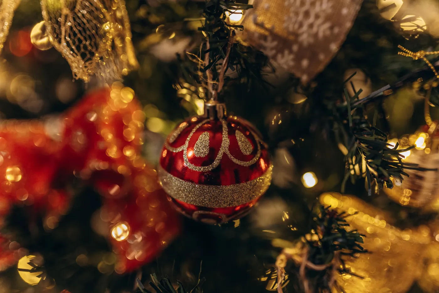 A close-up view of a decorated Christmas tree with red ornaments and ribbon.