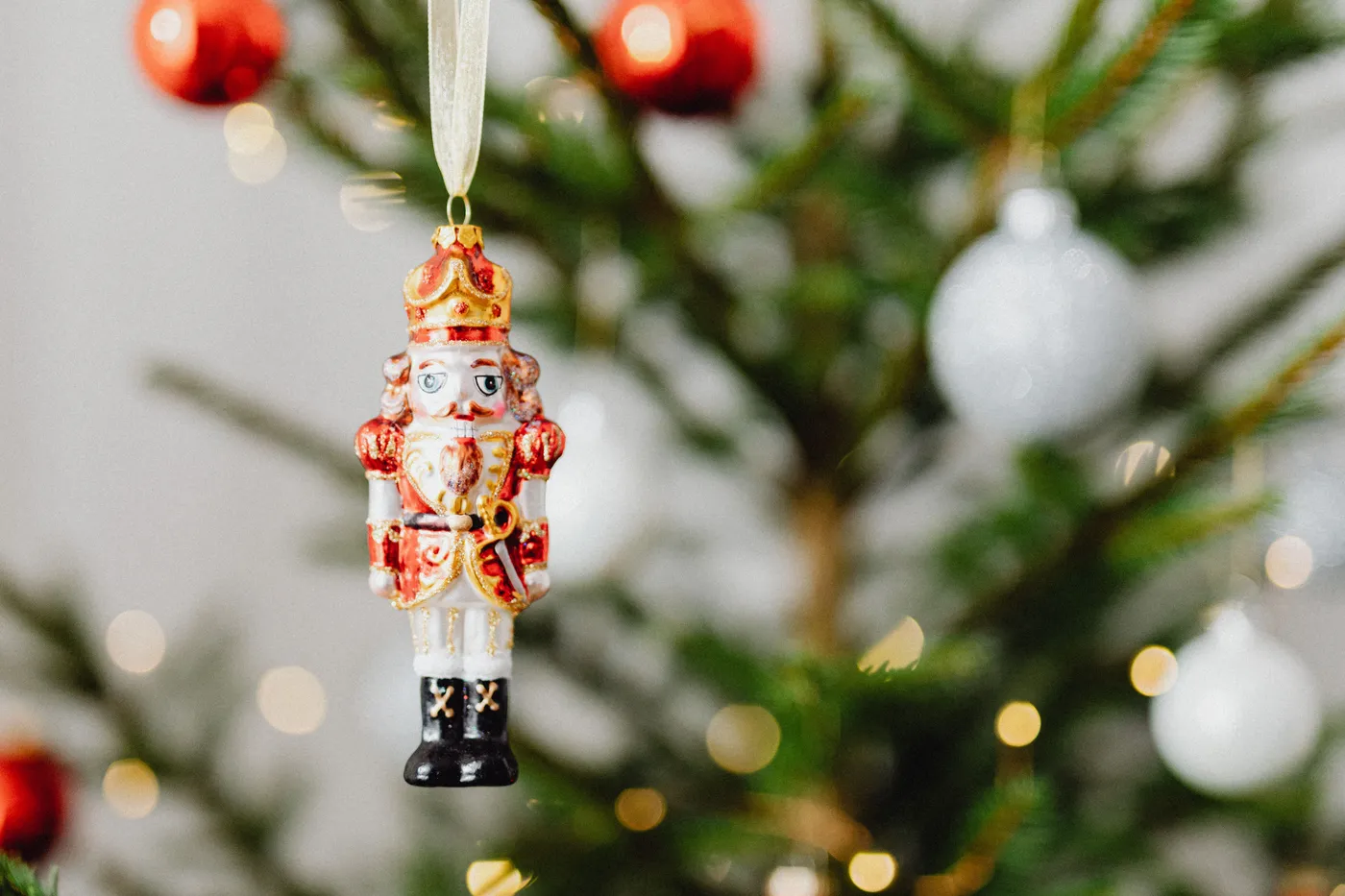 A colorful nutcracker ornament hanging on a decorated Christmas tree.