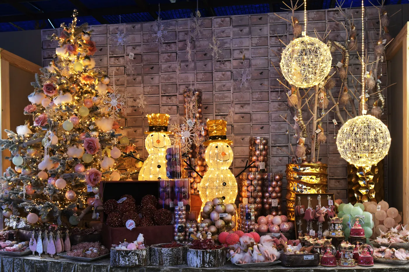 A cozy indoor Christmas display featuring ornaments, a tree, and glowing snowmen.