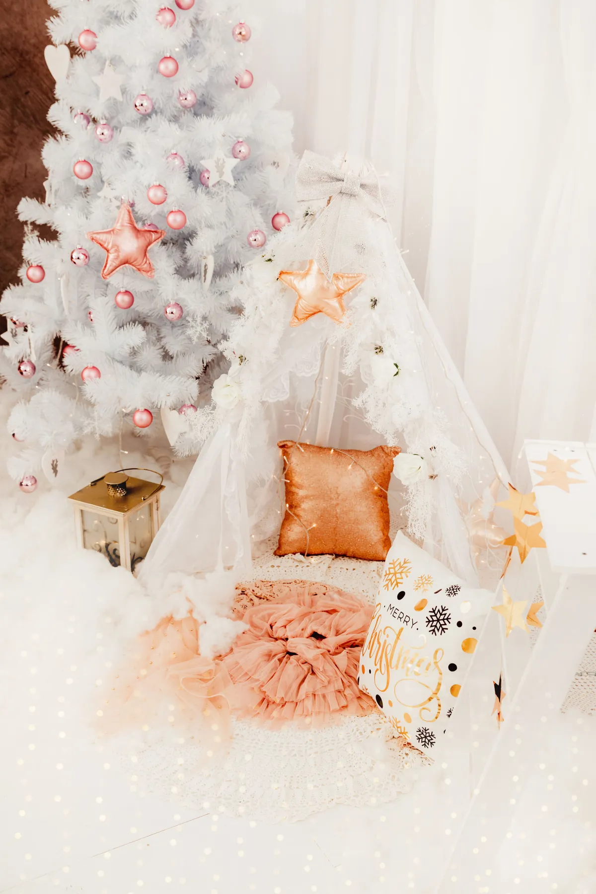 A cozy indoor Christmas setting featuring a white tree and decorative tent, perfect for holiday inspiration.