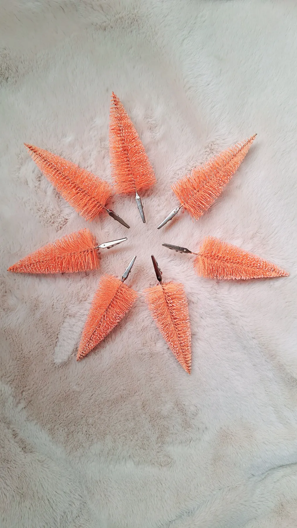 A creative flat lay of orange bottle brush trees in a star pattern on a neutral surface.