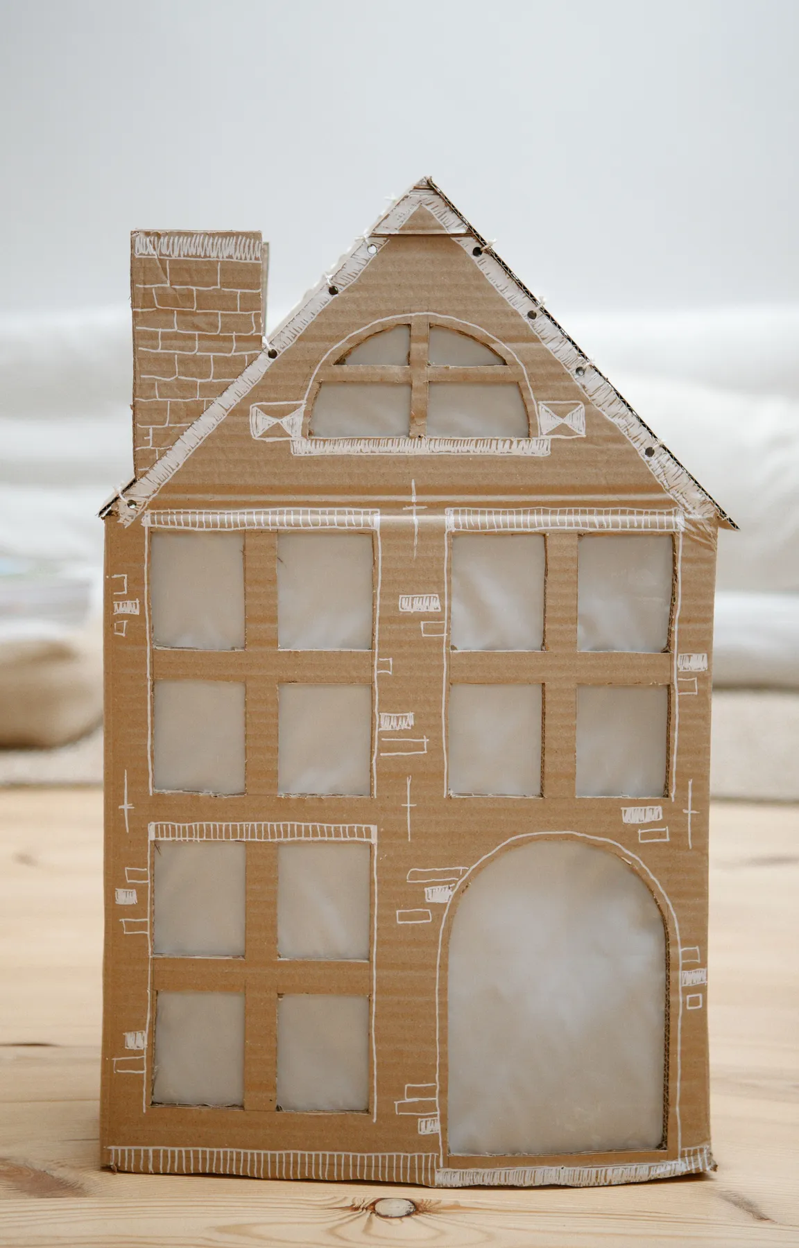 A detailed cardboard Christmas house model with decorative elements, perfect for holiday décor.