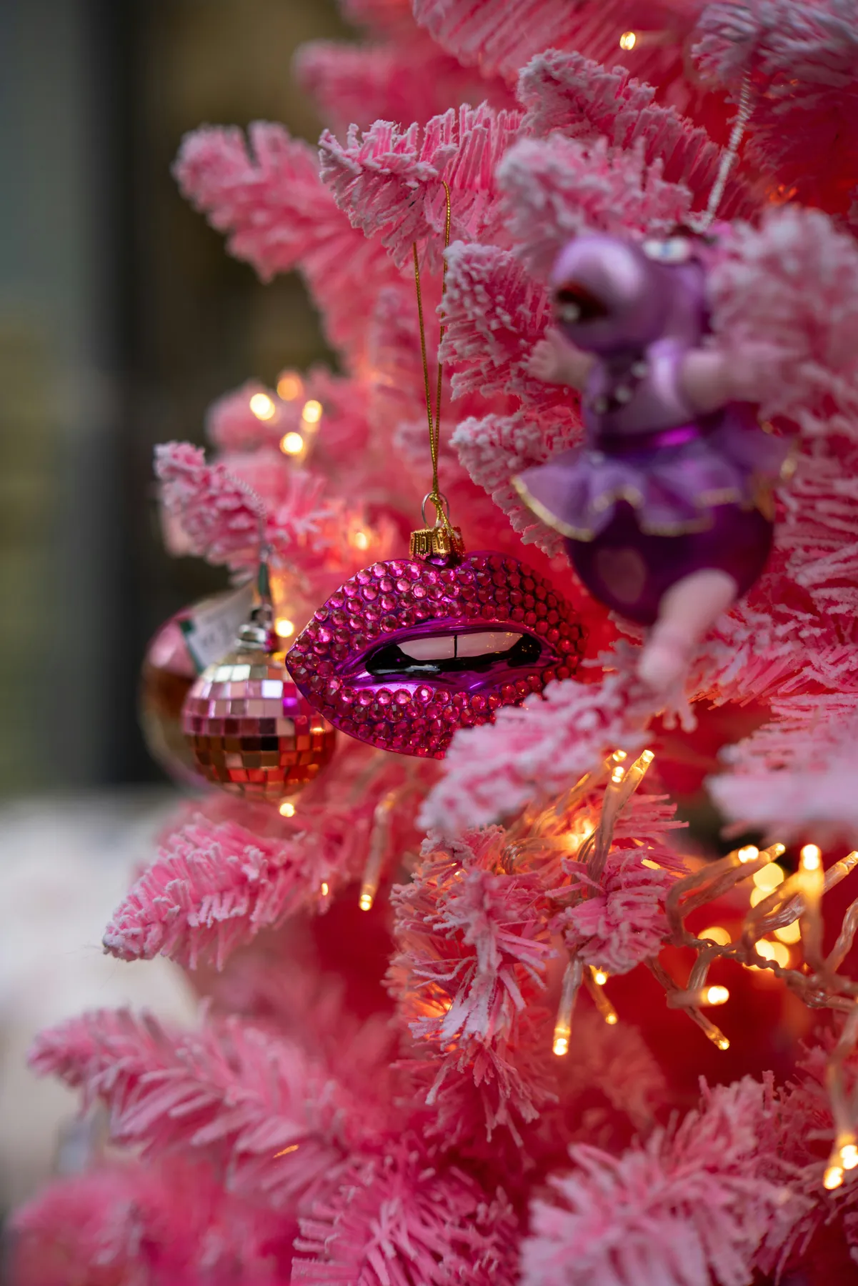 A pink christmas tree with ornaments on it