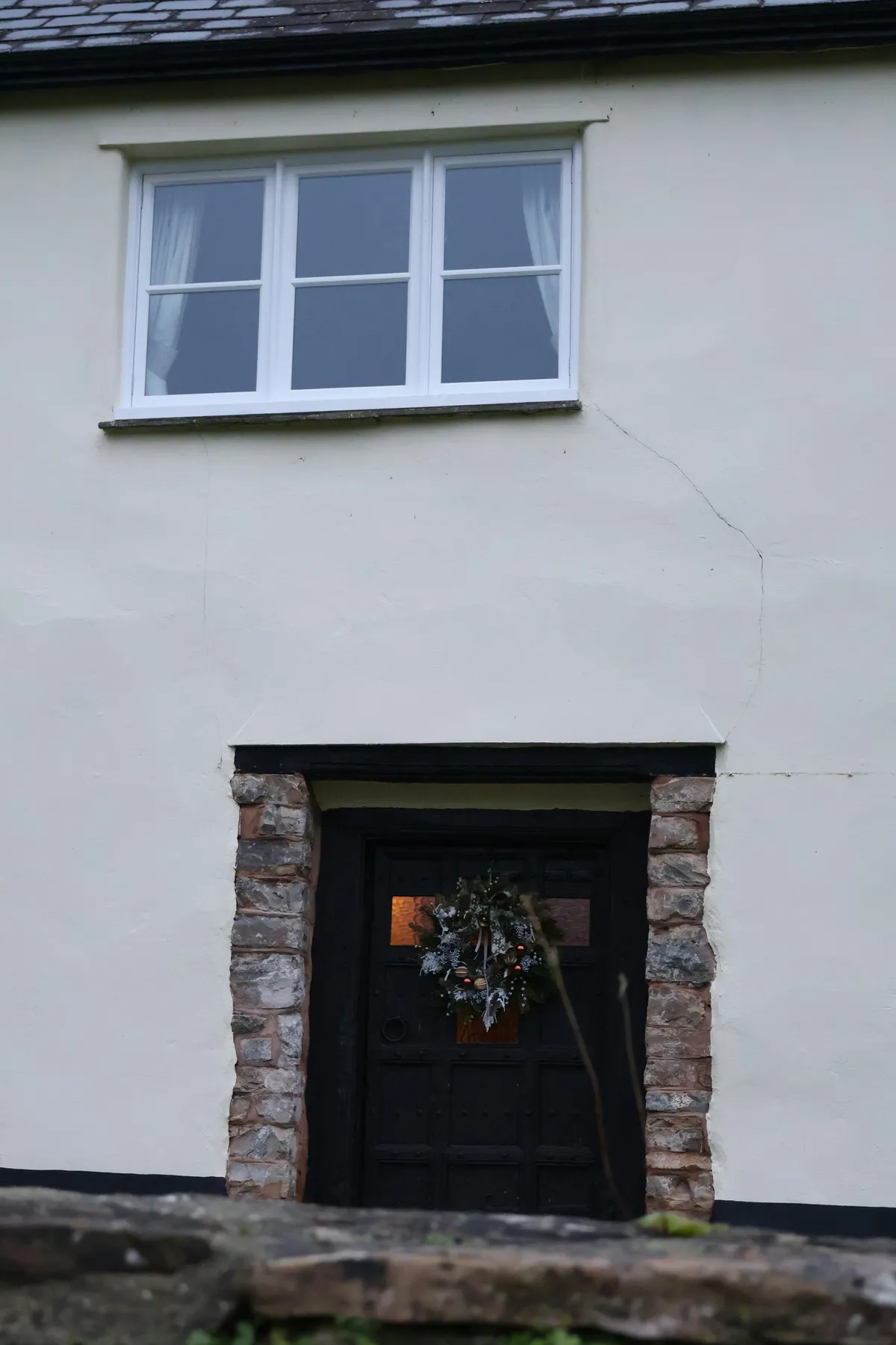 A rustic doorway with a wreath and a window above