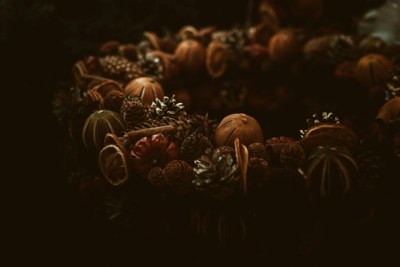 A rustic wreath with dried fruit and pinecones