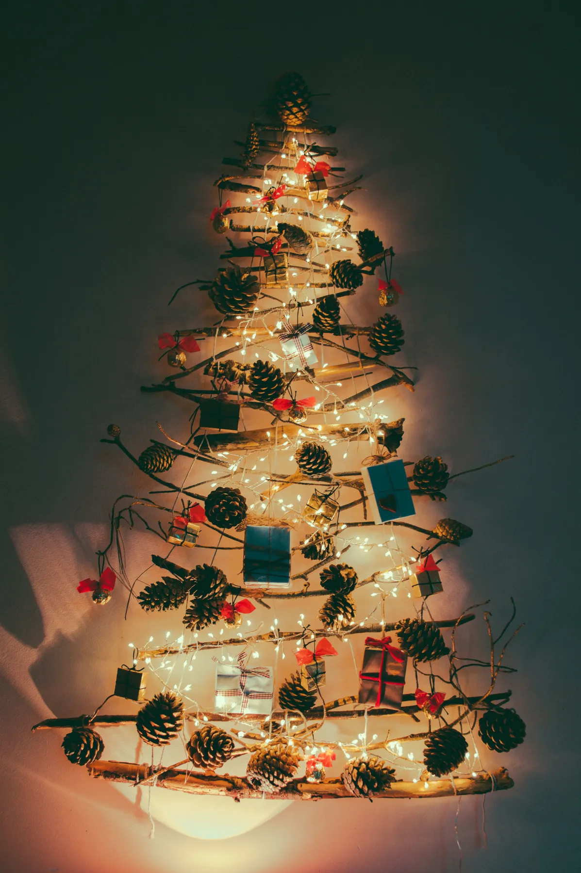 A unique Christmas tree design featuring pinecones and lights on a wall setup, creating a festive ambiance.