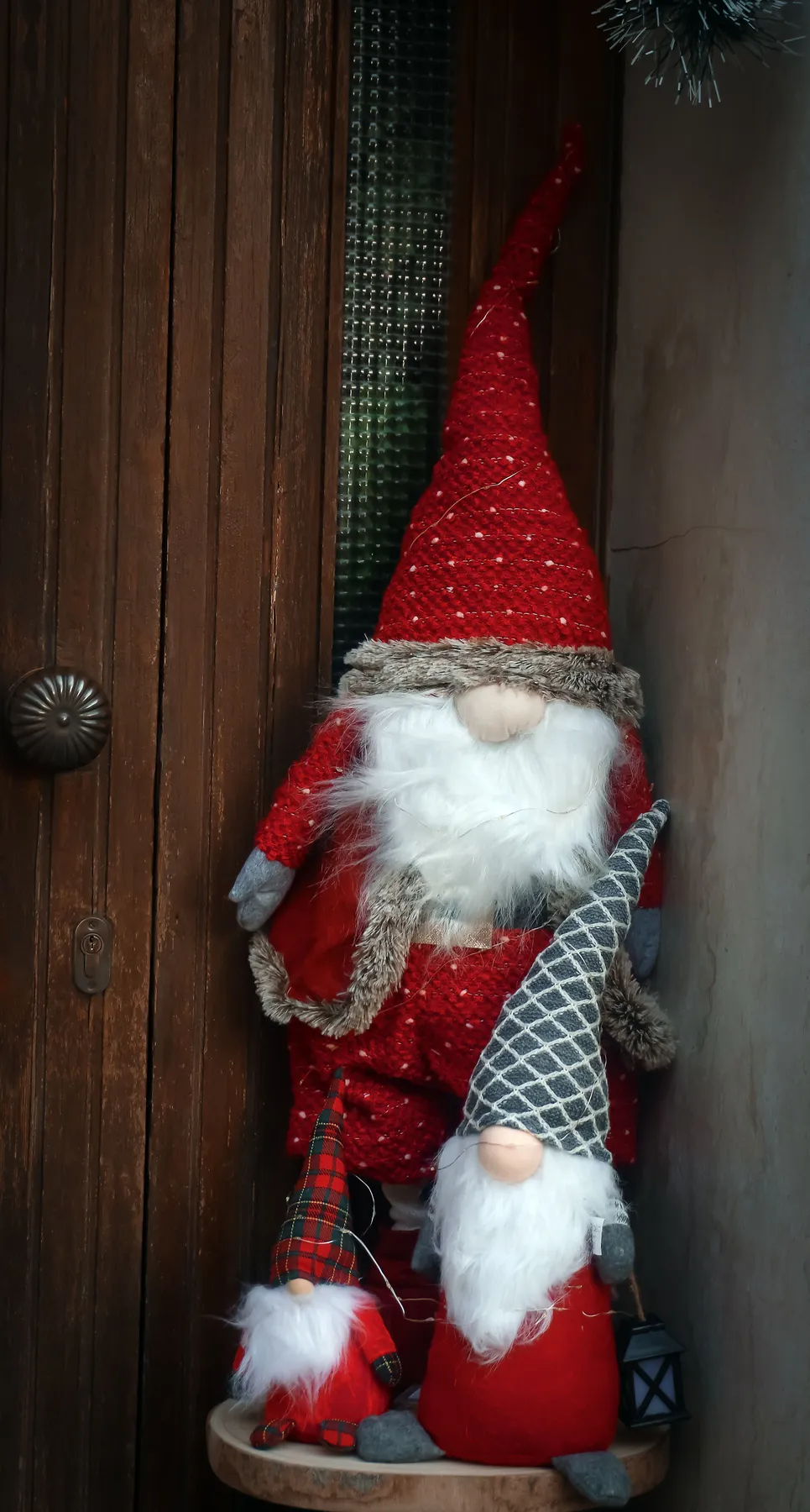 Adorable Christmas gnomes in red and gray attire brighten a cozy doorstep.