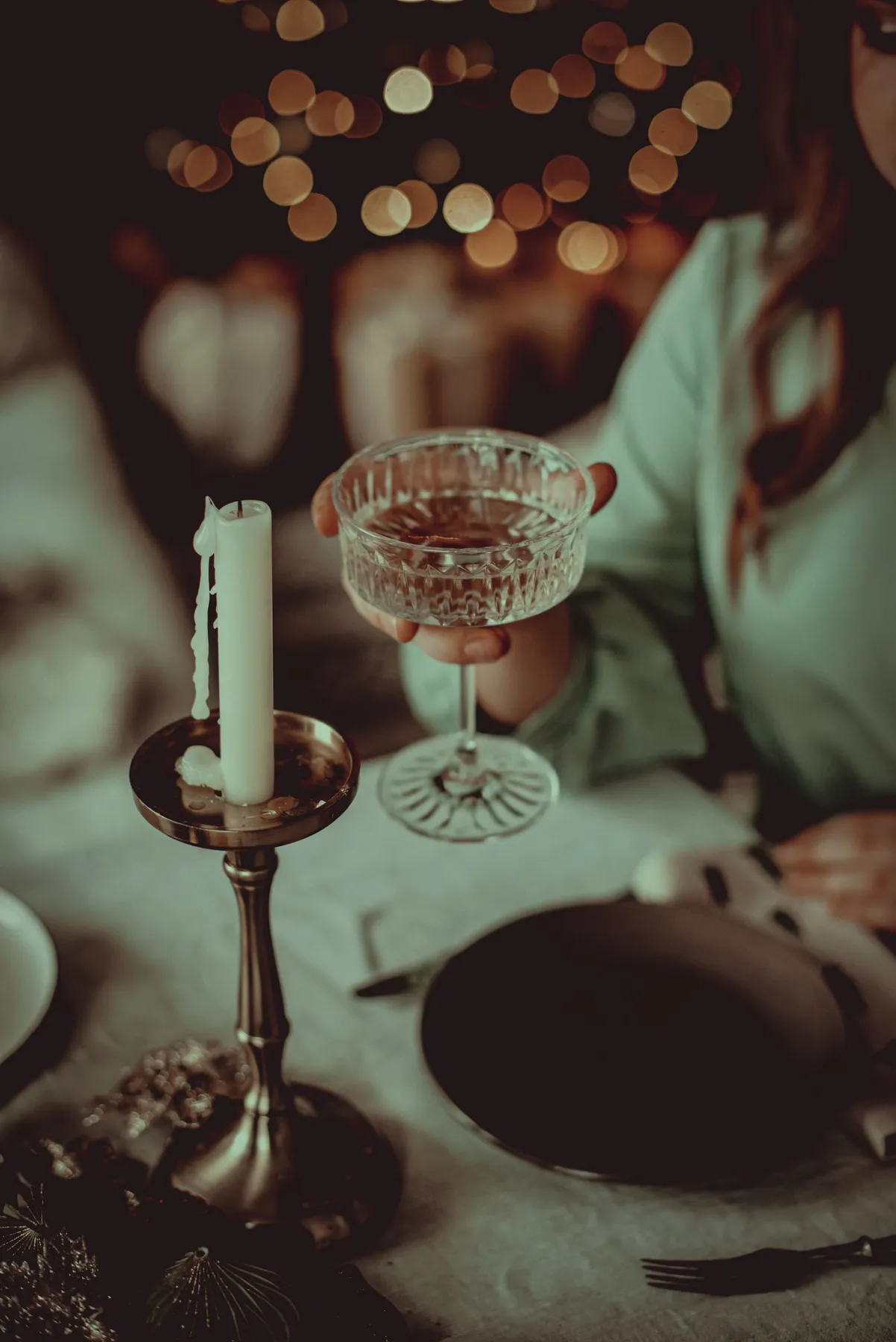 An elegant dinner party setting with a crystal glass and candlelight ambiance, perfect for festive occasions.