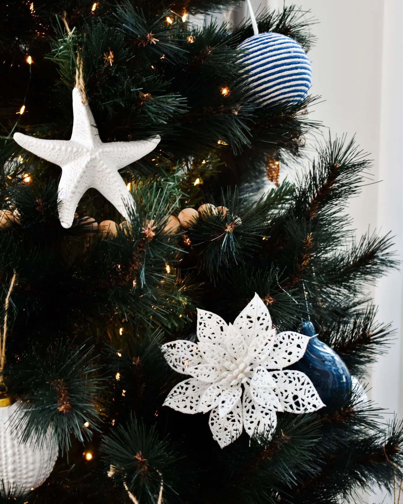 Close-up of a Christmas tree adorned with unique starfish and floral ornaments for a coastal holiday theme.