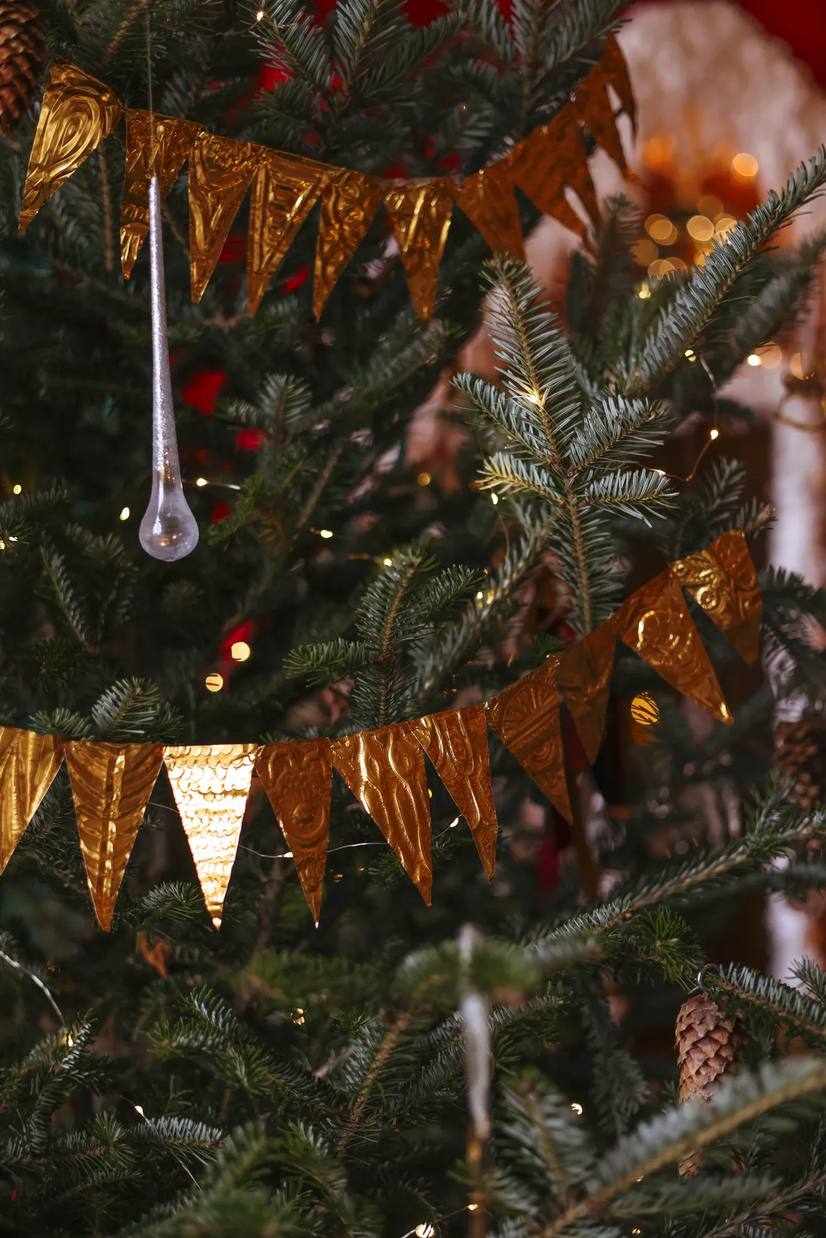 Close-up of a decorated Christmas tree with golden banners and ornaments indoors.