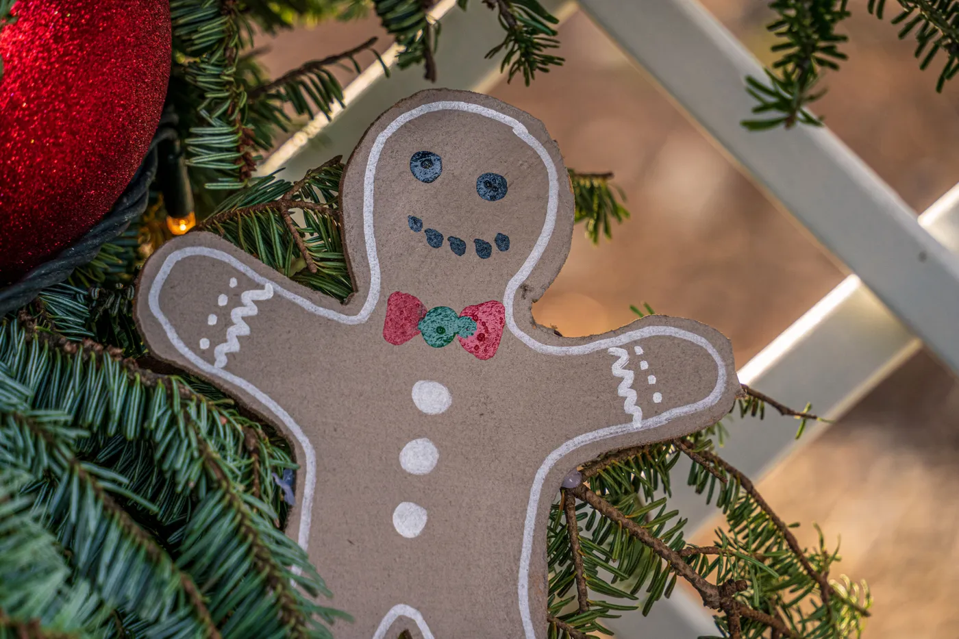 Close-up of a gingerbread ornament on a decorated Christmas tree branch.
