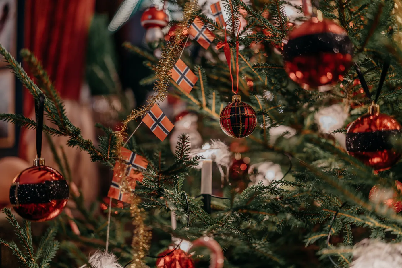 Close-up of decorated Christmas tree with red balls and flags, creating a festive atmosphere.