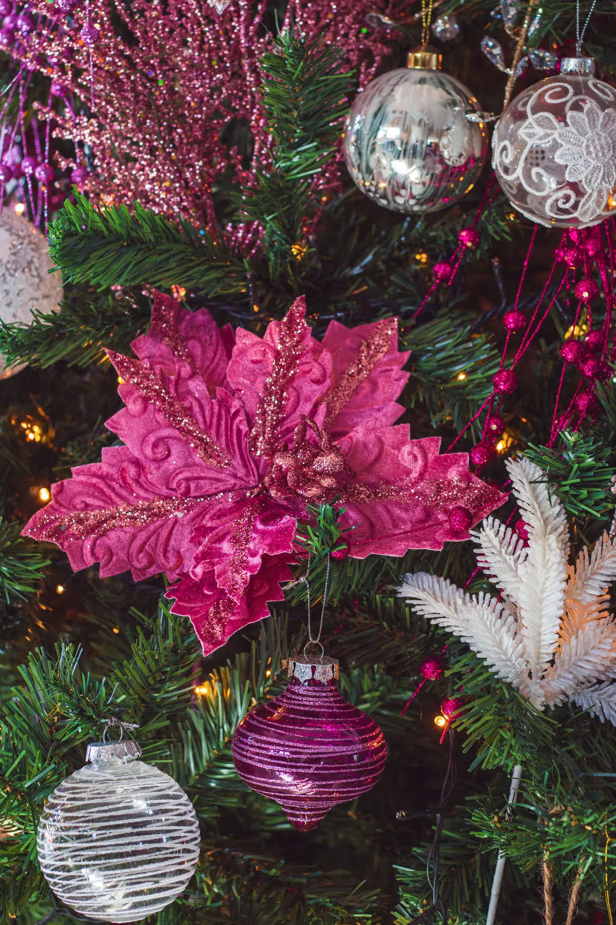 Close-up of festive Christmas tree adorned with pink baubles and floral decorations.