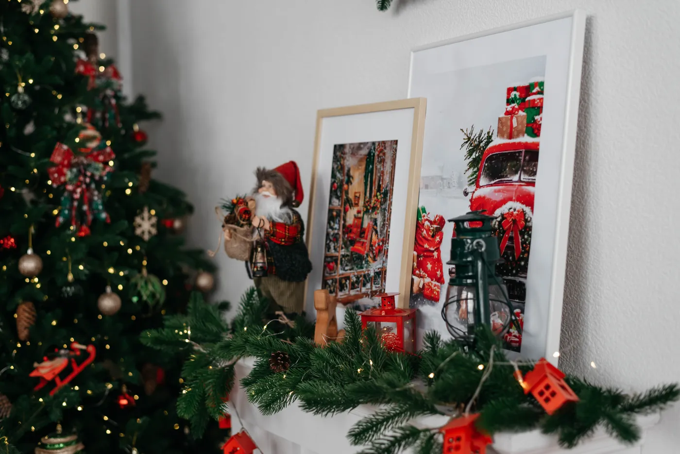 Cozy Christmas mantel with festive decorations, framed art and a holiday tree.