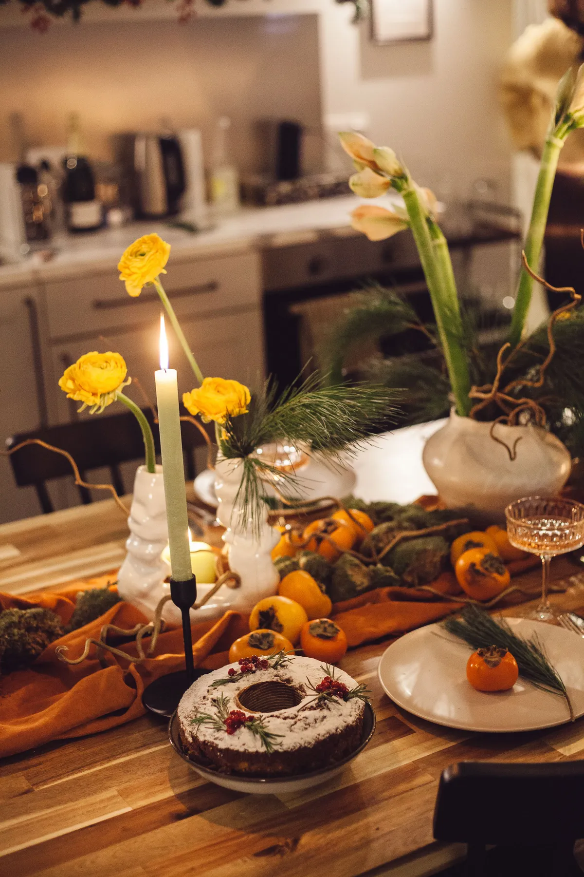 Cozy festive table setting with cake, candles, and floral decorations for a holiday celebration.