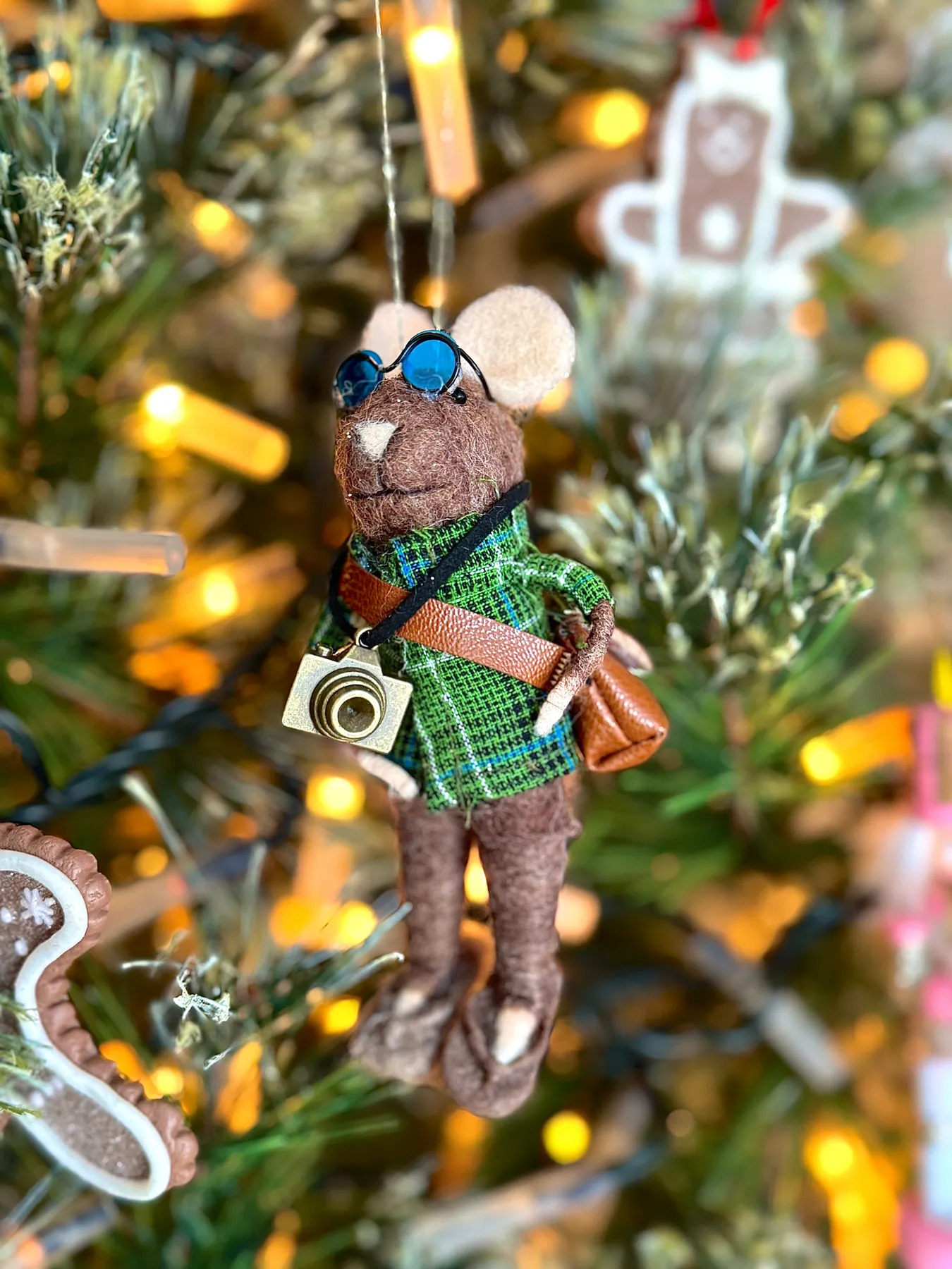 Cute felt mouse ornament with camera hanging on a decorated Christmas tree.