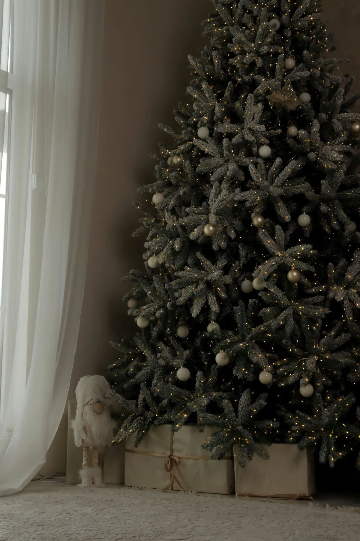 Decorated christmas tree with gifts by window