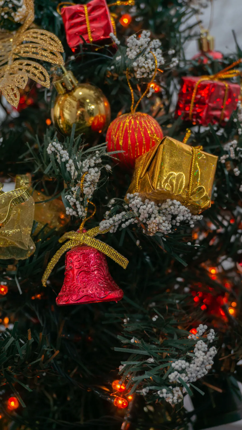 Decorated Christmas tree with red and gold ornaments, lights and foliage.