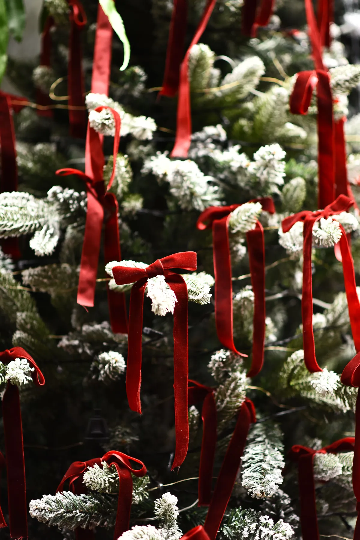 Decorated Christmas tree with red bows and artificial snow, creating a festive holiday atmosphere.