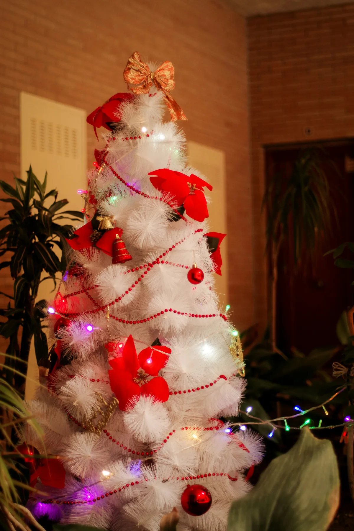Decorated white christmas tree with red ornaments and gold ornaments
