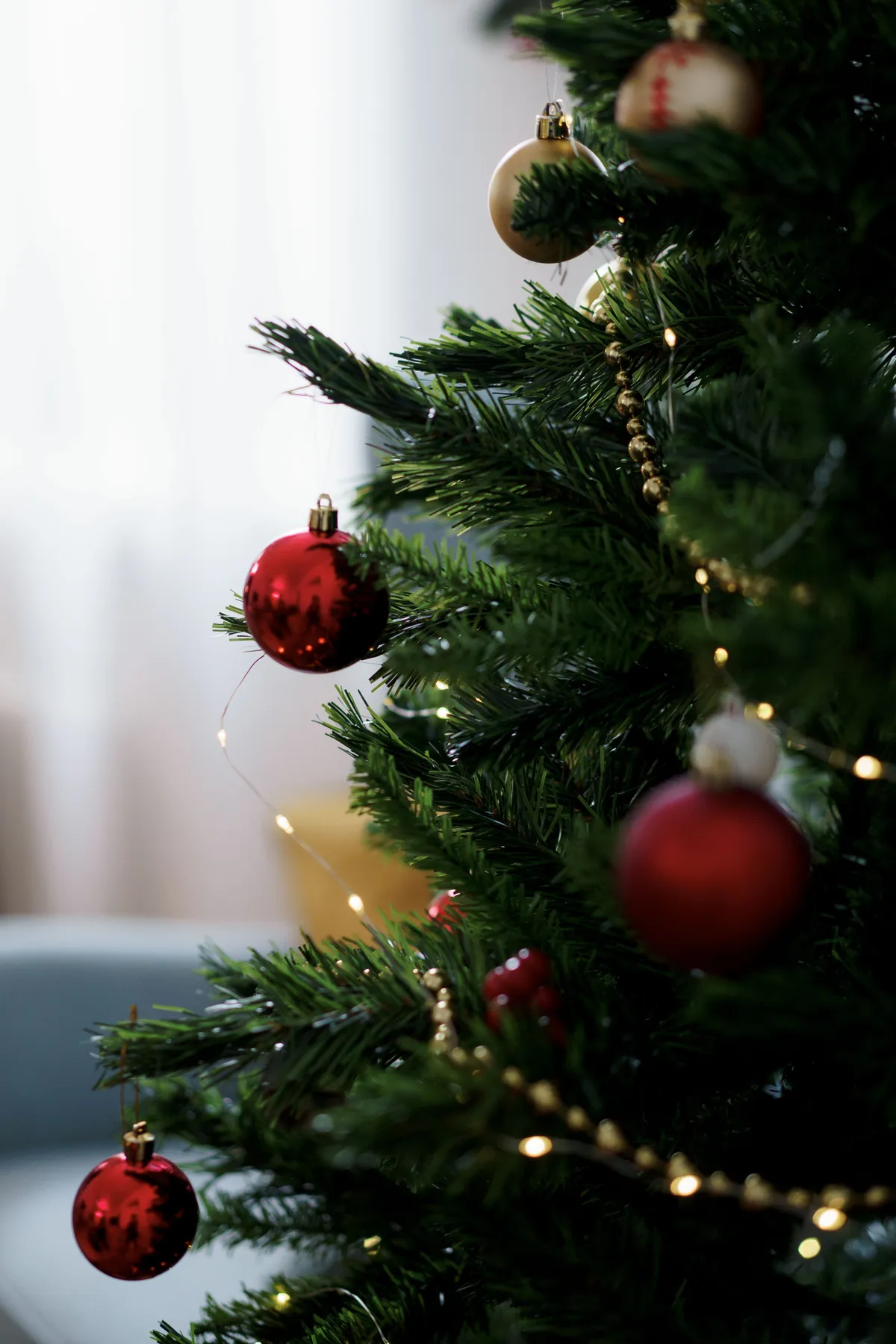 Elegant Christmas tree adorned with red baubles and golden garland, capturing a festive atmosphere.