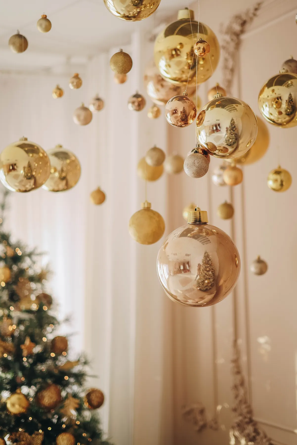 Elegant golden Christmas ornaments hanging in a festive living room with a tree.