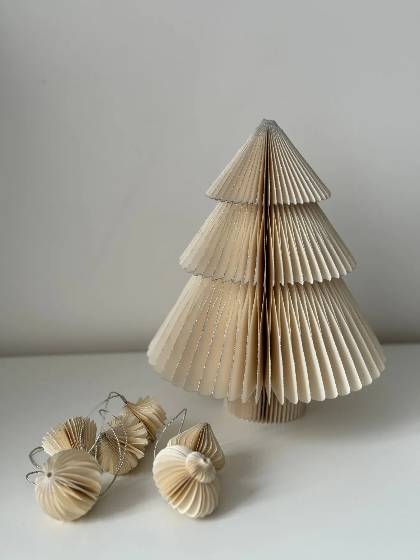 Elegant origami Christmas tree with paper ornaments on gray background.