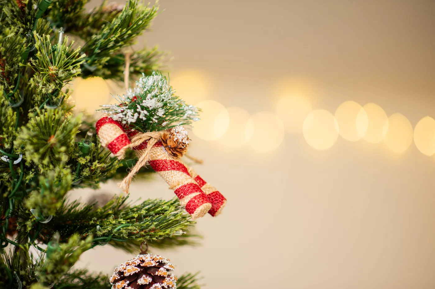 Festive Christmas tree ornament featuring red ribbon and pinecones with a bokeh backdrop.