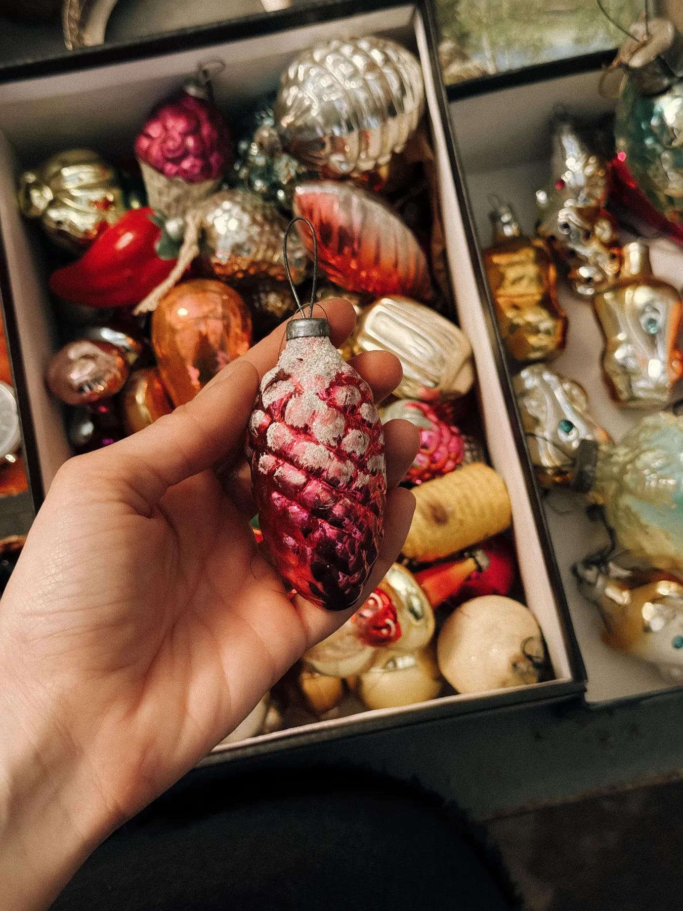 Hand holding a vintage Christmas ornament with a collection of colorful baubles.