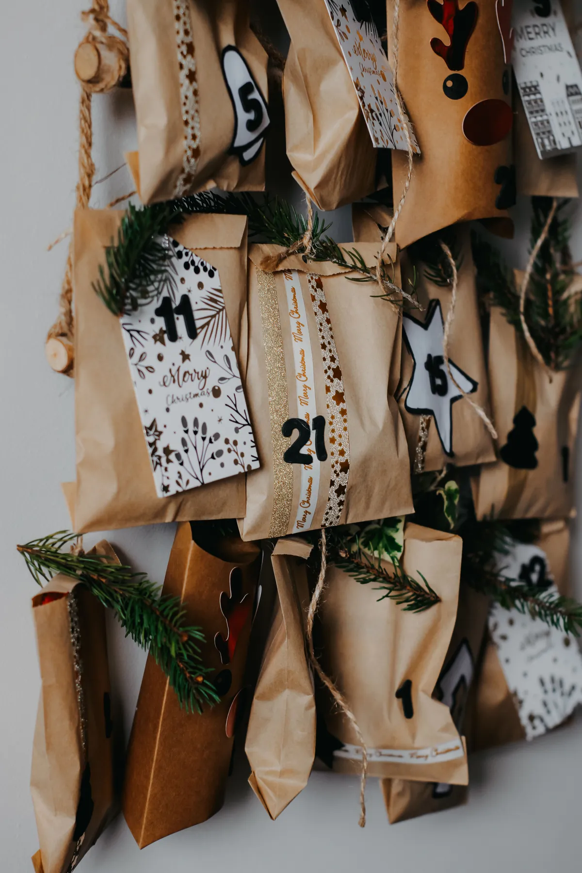 Handmade advent calendar with paper bags and decorative elements hanging on a wall.