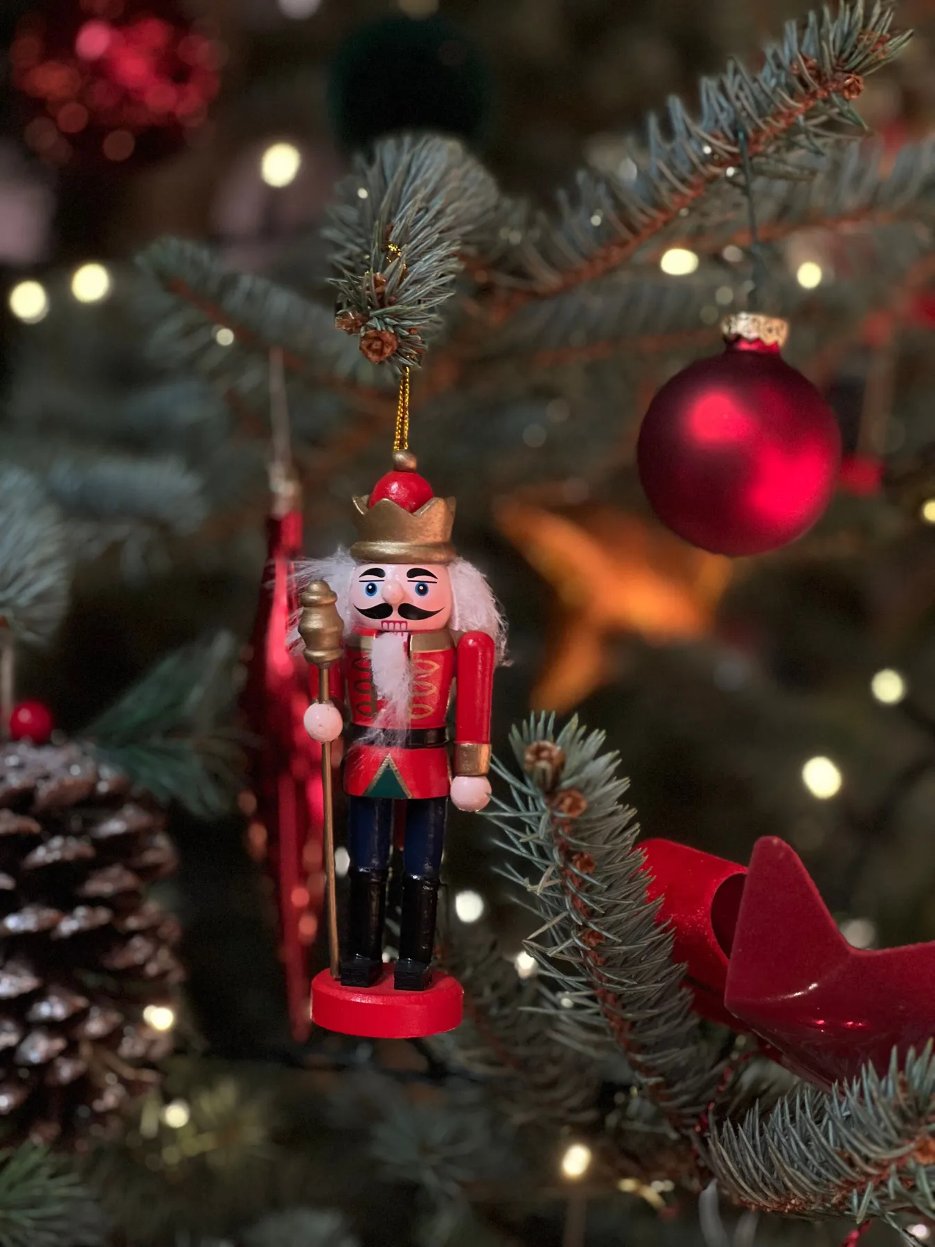 Nutcracker ornament hangs, adding charm to a festive Christmas tree with lights.