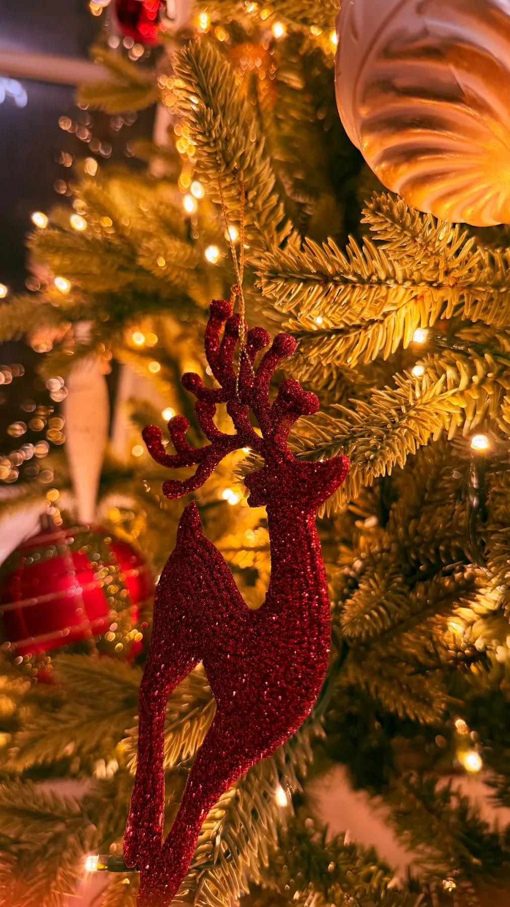 Red glitter reindeer ornament on a decorated christmas tree