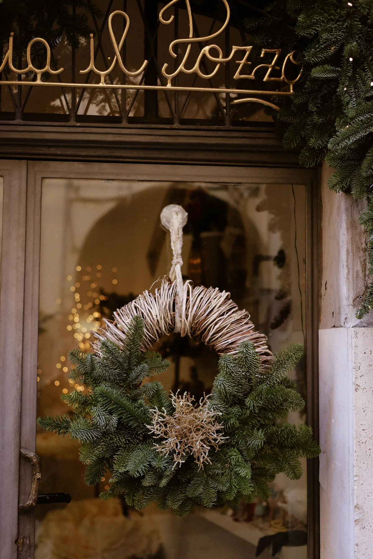 Traditional Christmas wreath adorning a glass door, creating a cozy festive atmosphere.