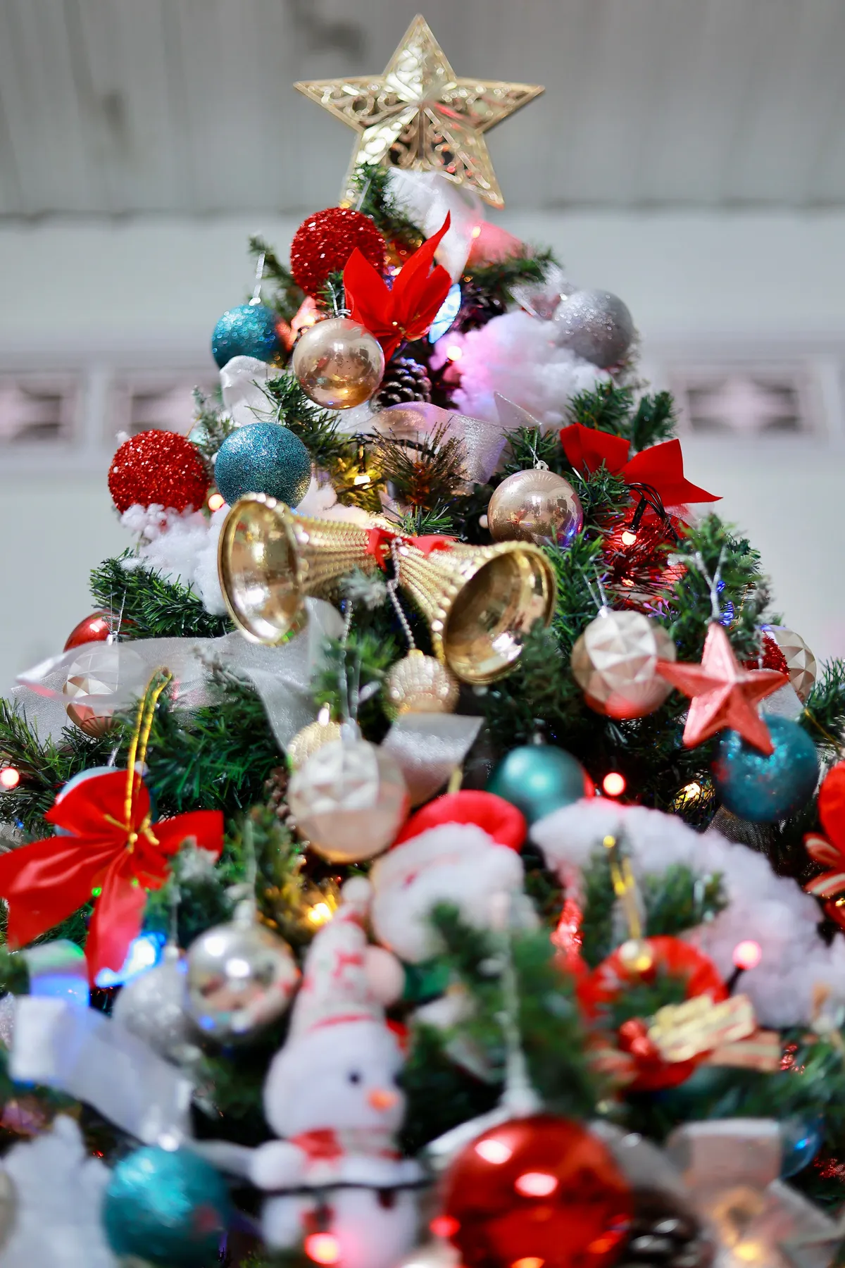 Vibrant Christmas tree decorated with ornaments, ribbons, and star topper.